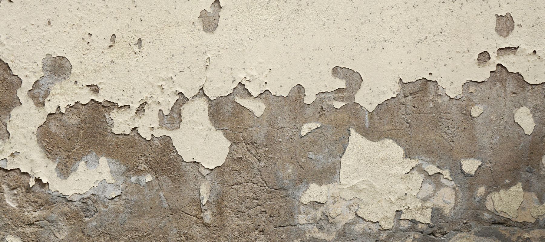 white paint flaking off of a concrete wall