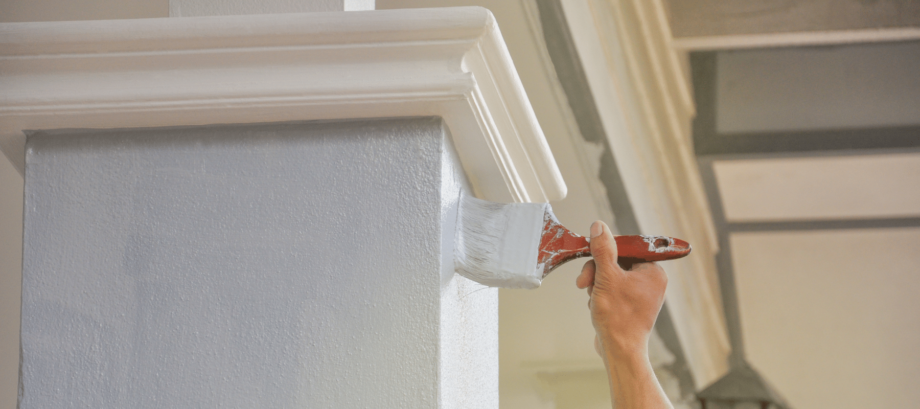 closeup of a person painting the exterior of a house