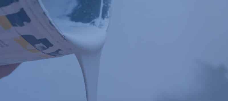 Close-up of white paint being poured from a can